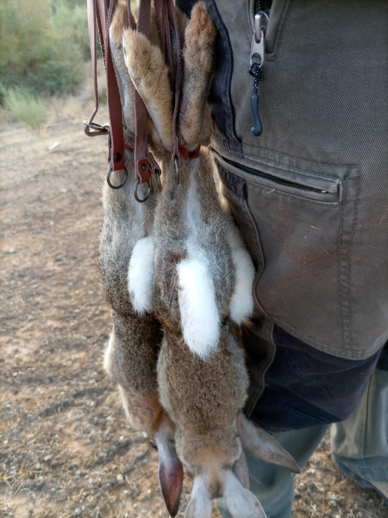 cazador de conejor con una percha de conejor muertos colgados 